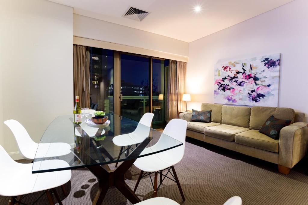 墨尔本Melbourne Royal Botanical Gardens 2BR的客厅配有玻璃桌和白色椅子