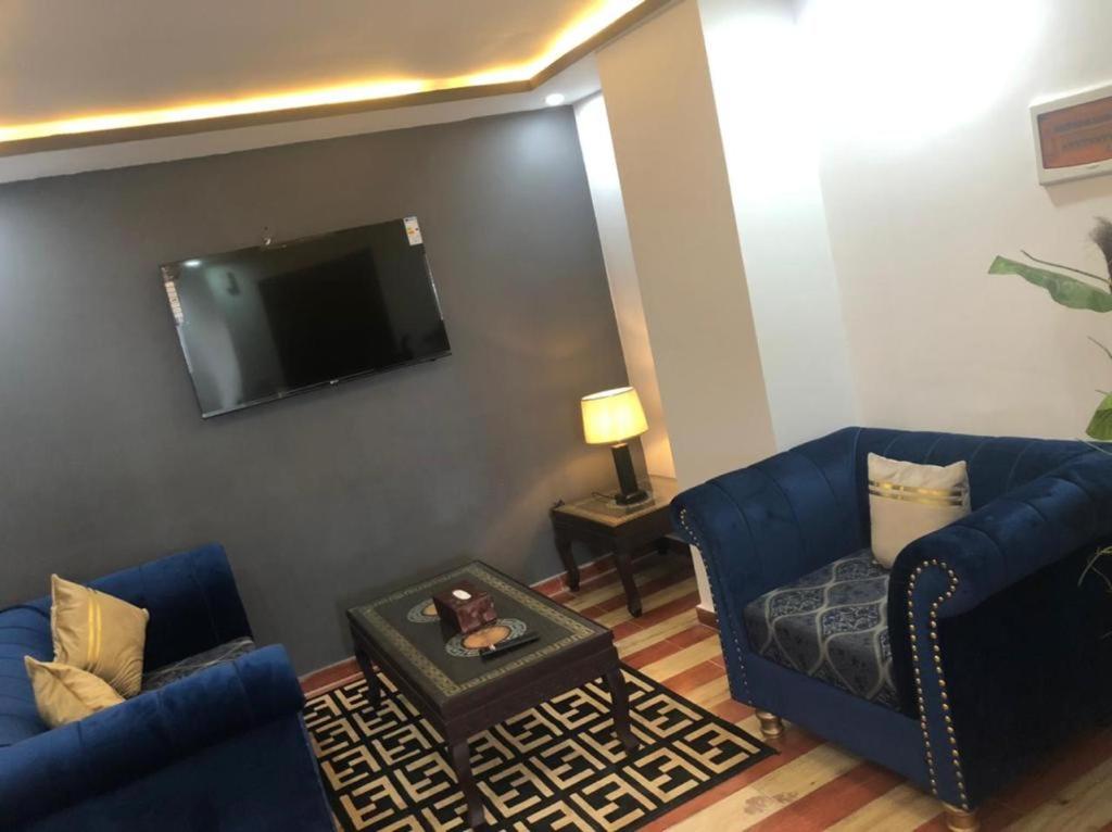 JhelumLux Aparts Jhelum的客厅配有2张蓝色沙发和1台平面电视