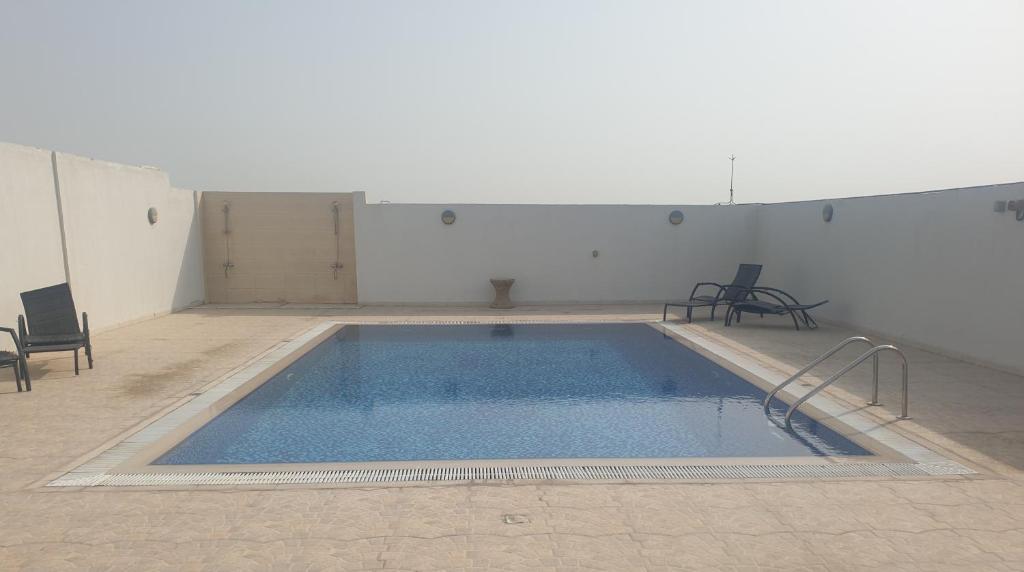 迪拜1-Bedroom Apartment Rental Unit With Pool in Dubai Land Residence Complex Dubai Al Ain Road的一个带椅子的房间的大型游泳池