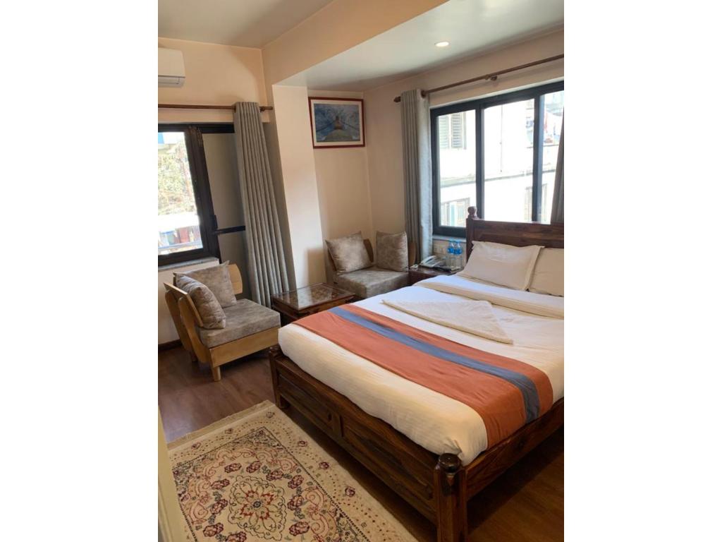 加德满都Hotel Ramanam的卧室配有床、椅子和窗户。