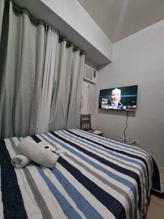 马尼拉Macks Awesome Place 204 NetflixFastWifi的一间卧室配有一张床,里面配有电视