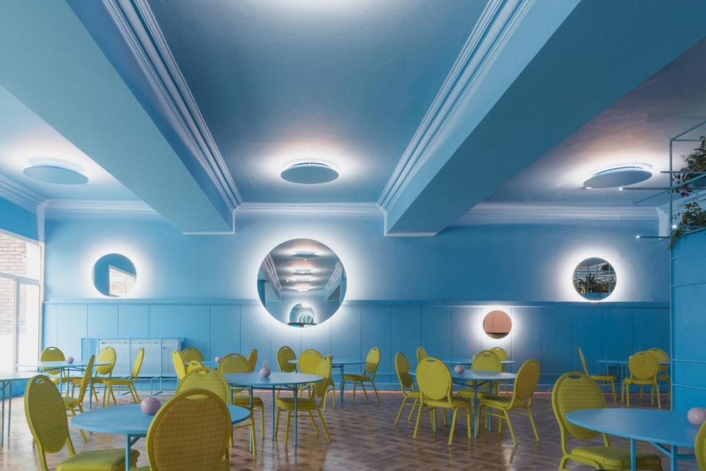 蒙得维的亚Selina Montevideo的一间拥有蓝色天花板和桌子及黄色椅子的用餐室