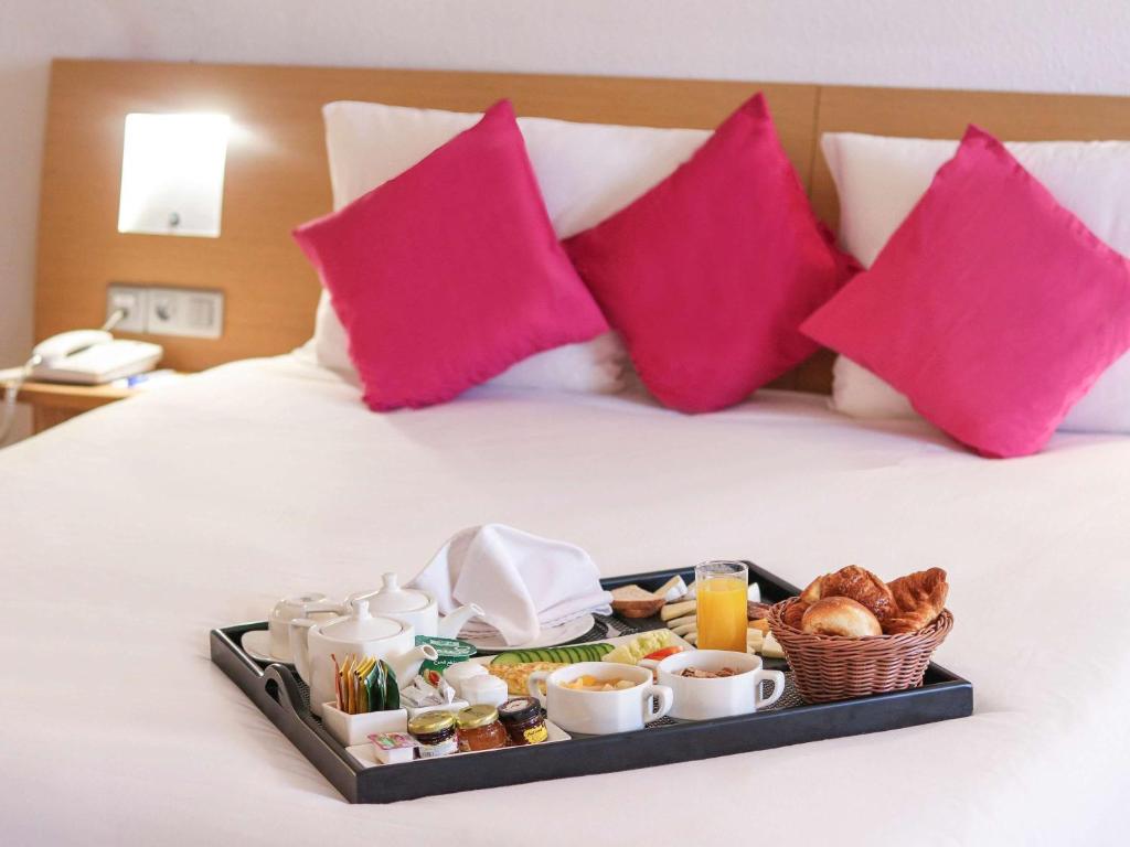 突尼斯诺富特突尼斯酒店的床上的早餐盘,有粉红色枕头