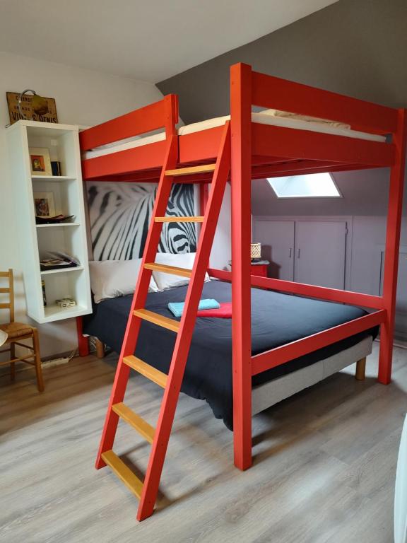 凯恩Studio au 2e étage de notre maison de ville的客房内的红色双层床,带梯子
