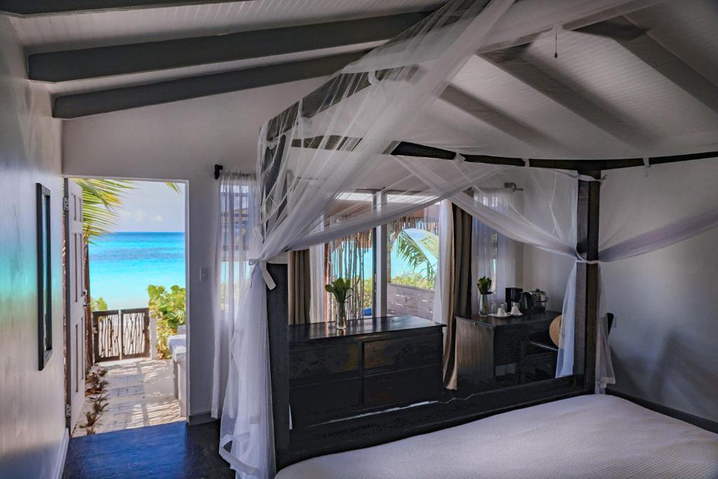 Conch Beach Cabins的一间卧室设有一张天蓬床,享有海景