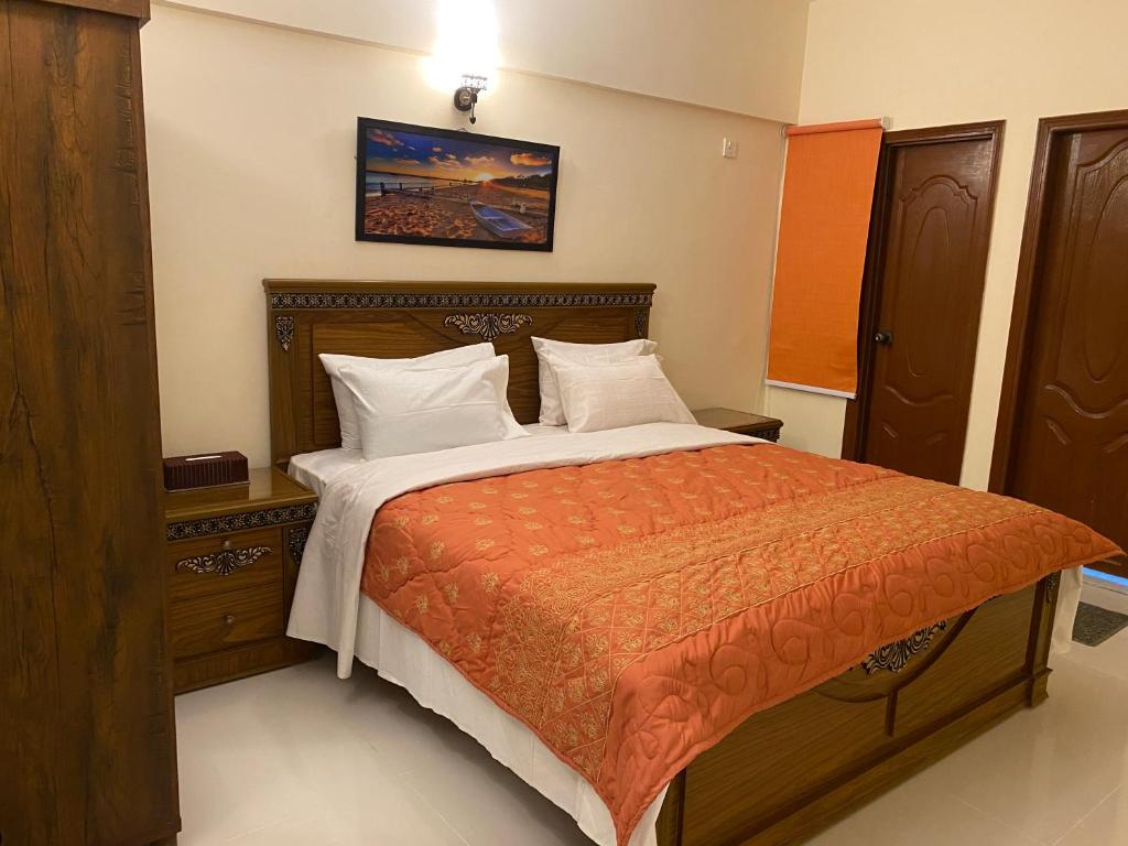 卡拉奇3 Bed Apartment的一间卧室配有一张带橙色棉被的床