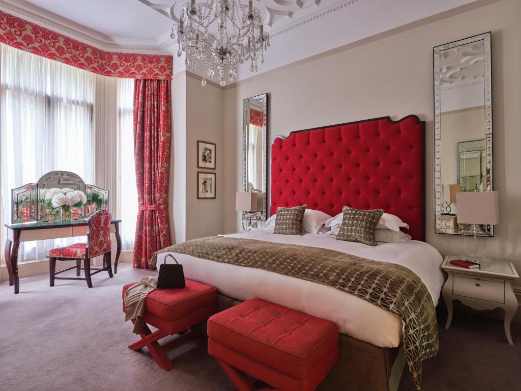 伦敦斯隆俱乐部公寓的一间卧室设有一张大床和红色床头板