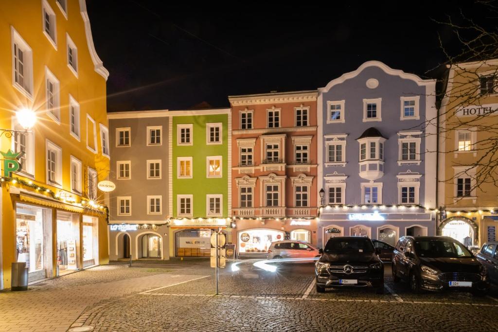 谢尔丁Loft Suite im modernen Style in Schärding的夜间的城市街道,汽车停在大楼前