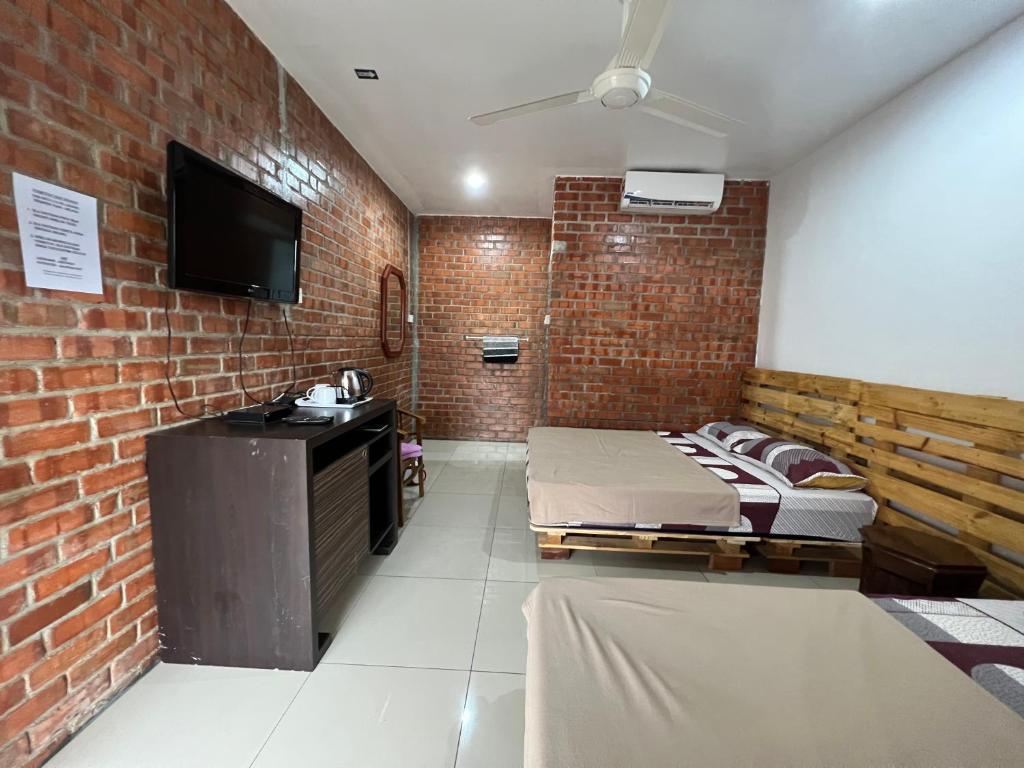 马六甲Ujud Sepakat Homestay的一间设有两张床和砖墙的房间