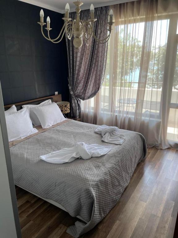 普里莫尔斯科Deluxe Apartments Приморско的一间卧室配有一张带白色床单和吊灯的床。