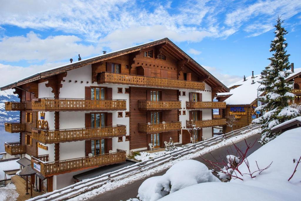 韦松纳Hôtel Chalet Royal的一座大建筑,设有雪地木制阳台