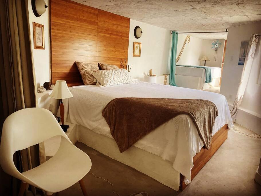 SheernessForever Beach Apartment的一间卧室配有一张大床和一张白色椅子