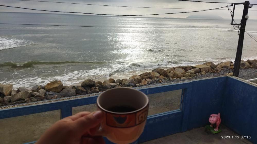 伊塔波阿Pé na areia apt superior的一边喝咖啡一边欣赏海景的人