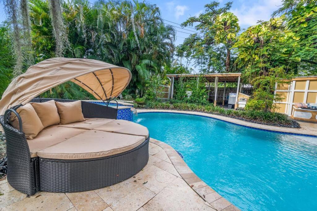 西棕榈滩Tropical Oasis Located Near Lake With Pool and Hot Tub的游泳池旁带遮阳伞的藤椅
