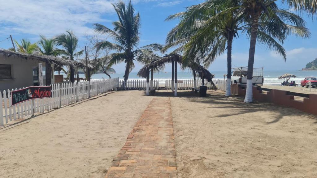 马萨特兰Casa a pie de playa isla de la piedra的棕榈树和白色围栏的沙滩