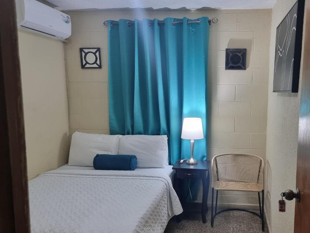 Nueva San SalvadorCat House的一间卧室配有一张蓝色窗帘的床