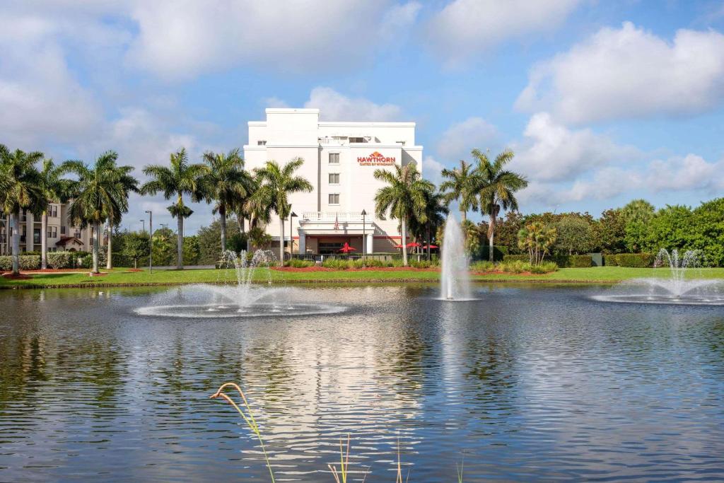 西棕榈滩西棕榈滩豪顿温德姆酒店的一座建筑前的池塘,有两个喷泉
