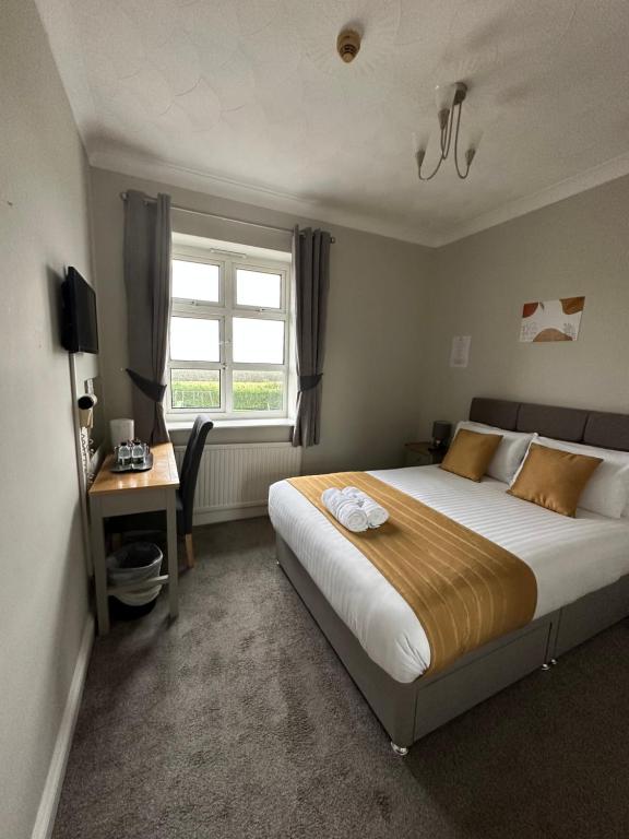 BattlesbridgeRettendon Lodge的一间卧室配有一张床、一张书桌和一个窗户。