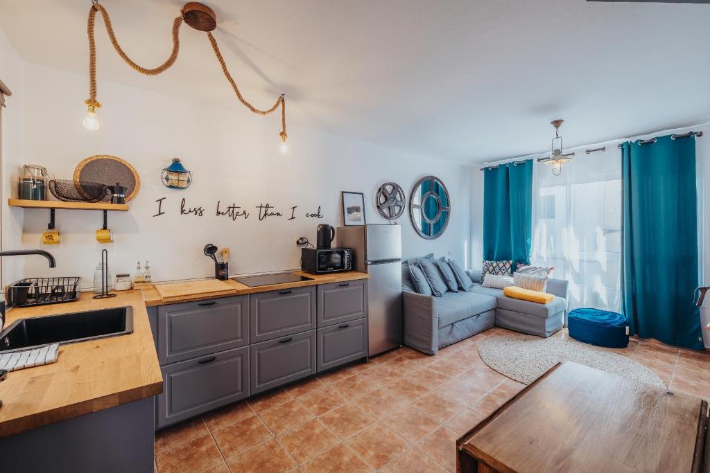 科蒂略Casa Allegranza的一间厨房和一间带蓝色窗帘及沙发的客厅