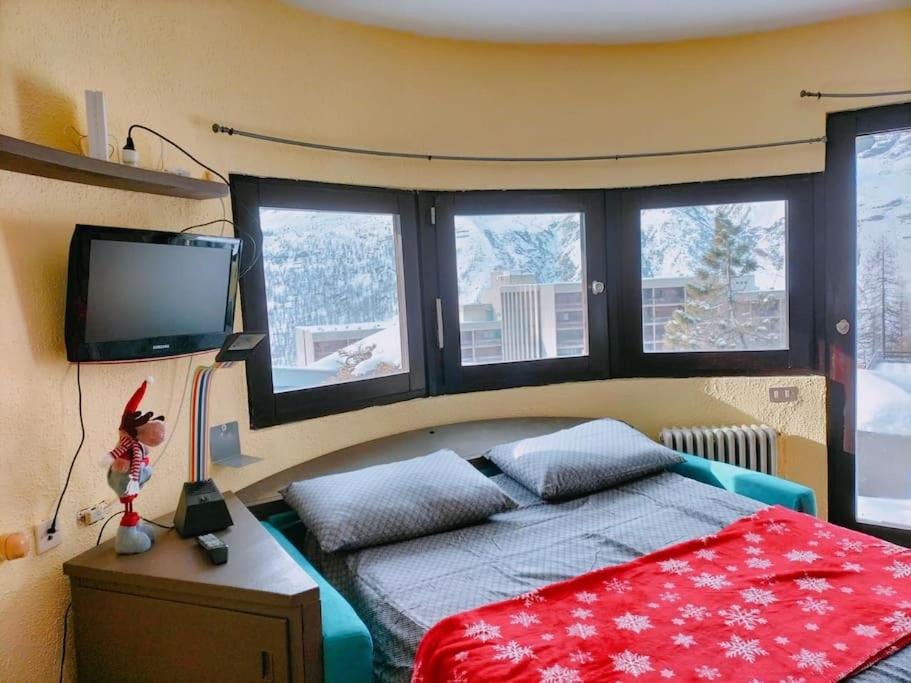 布勒伊-切尔维尼亚Cozy little studio in cervinia的一间卧室设有一张床、一台电视和窗户。