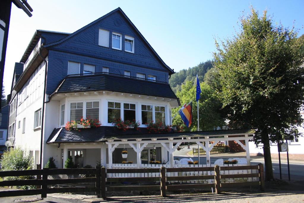 施马伦贝格Gasthof-Pension Hunaustuben的蓝色和白色的房子,前面有栅栏