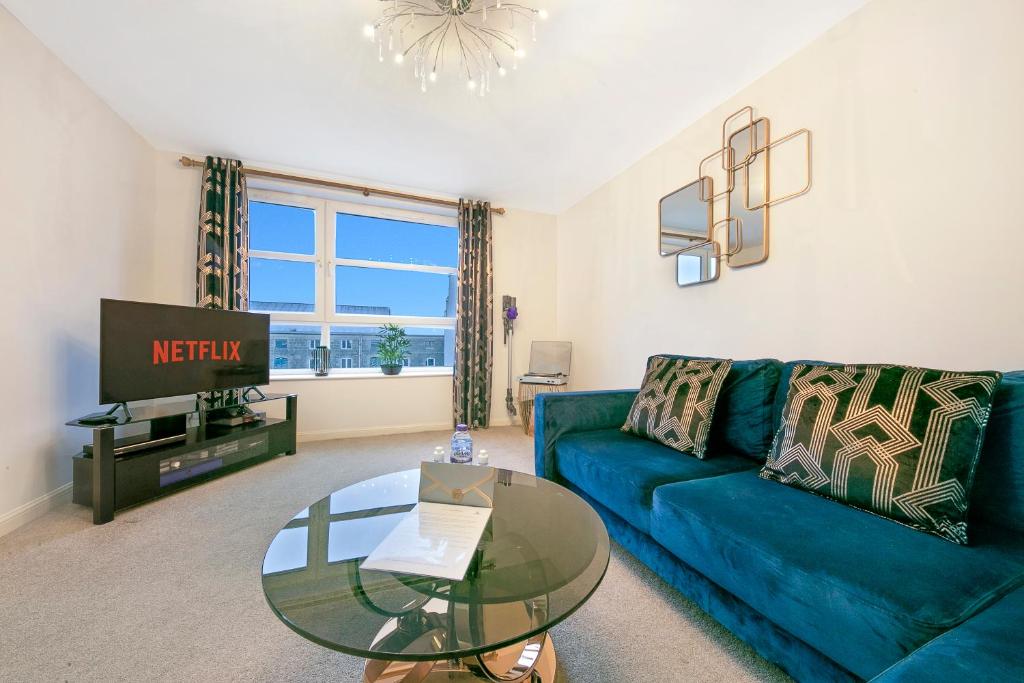 阿伯丁Kings Lodge - Grampian Lettings Ltd的客厅配有蓝色的沙发和玻璃桌