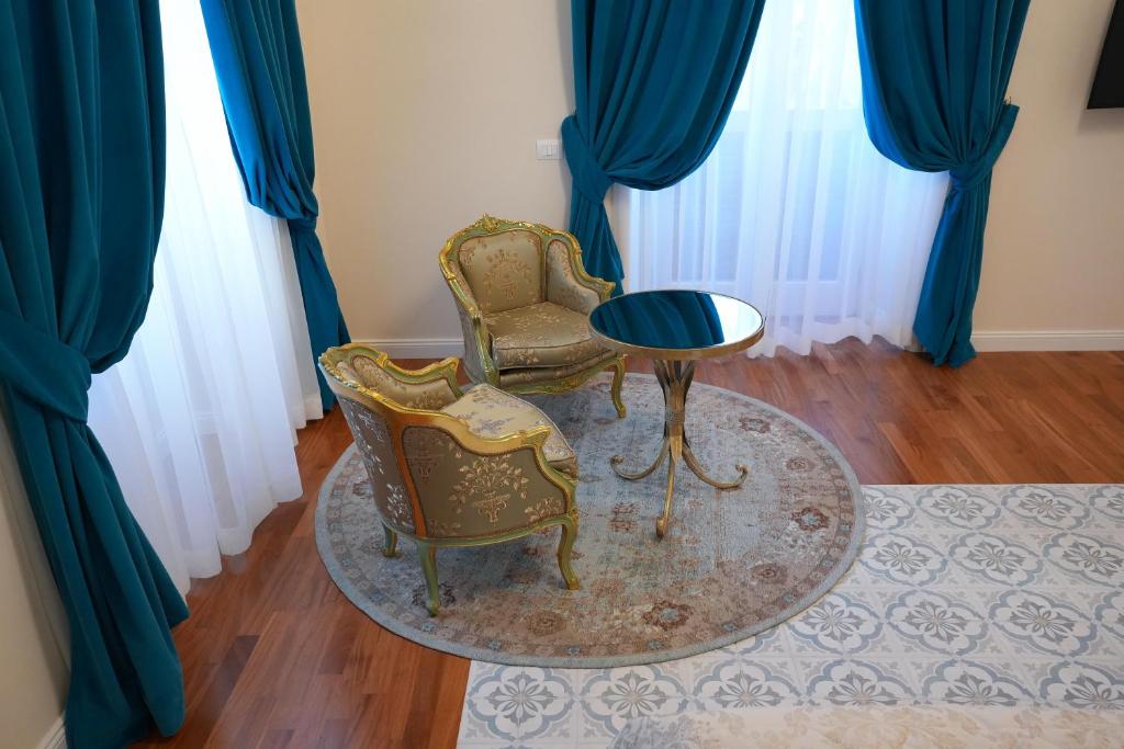 卡利亚里Rosetta Burger Queen的配有蓝色窗帘的客房内的2把椅子和1张桌子