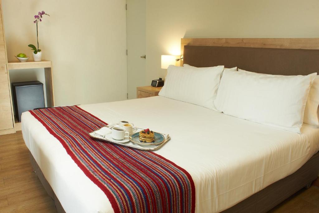 利马Hotel Estelar San Isidro的一间酒店客房,配有一张床铺,上面放着一个食物托盘