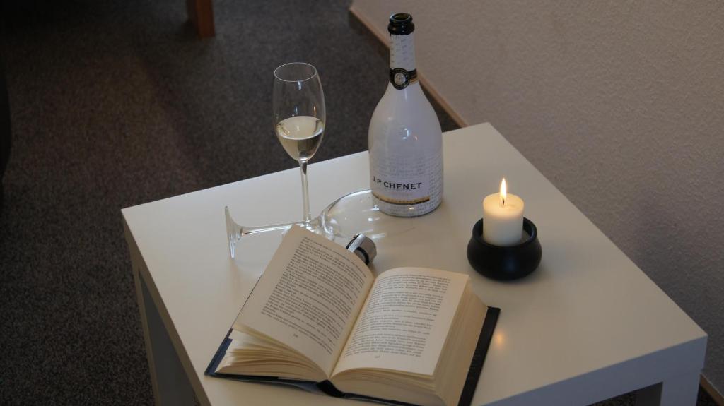 瓦伦Ferienapartments Sonnenhof的一张桌子,上面放着一本书,一瓶葡萄酒和蜡烛