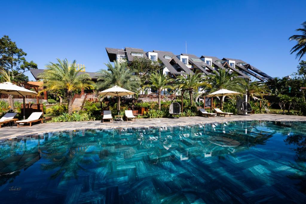 Buôn JuHami Garden - Authentic & Natural Resort的一个带椅子和遮阳伞的大型游泳池