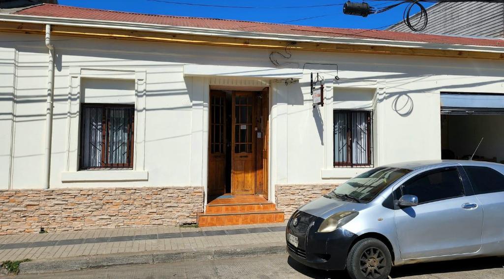 孔斯蒂图西翁Hospedaje Ahumada的前面有一辆汽车停放的白色房子