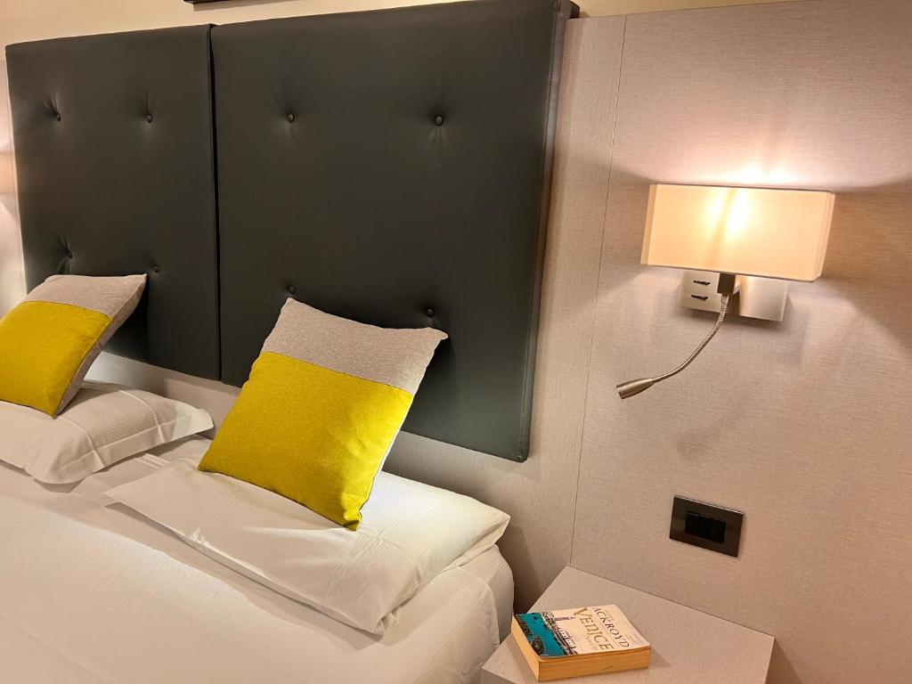梅斯特奥罗拉酒店的客房配有一张带黄色枕头和灯的床。