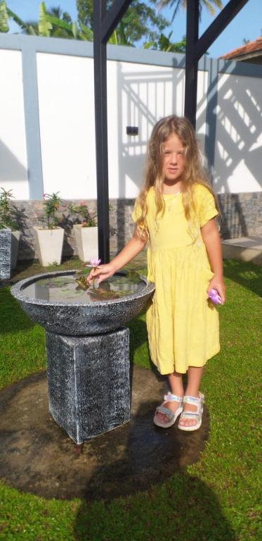 坦加拉White Queen Residence的站在喷泉旁的黄色连衣裙的小女孩