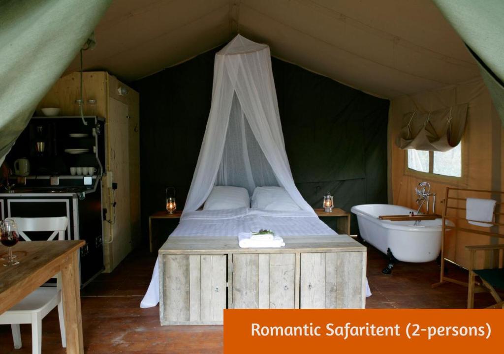 霍尔滕Safaritents & Glamping by Outdoors的一间卧室配有一张床,帐篷内设有一个浴缸