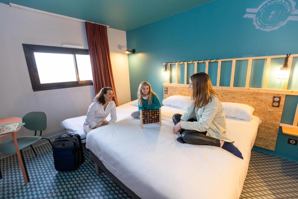 勒阿弗尔Birgit Hôtel Le Havre Centre的两名女孩坐在酒店房间的床边