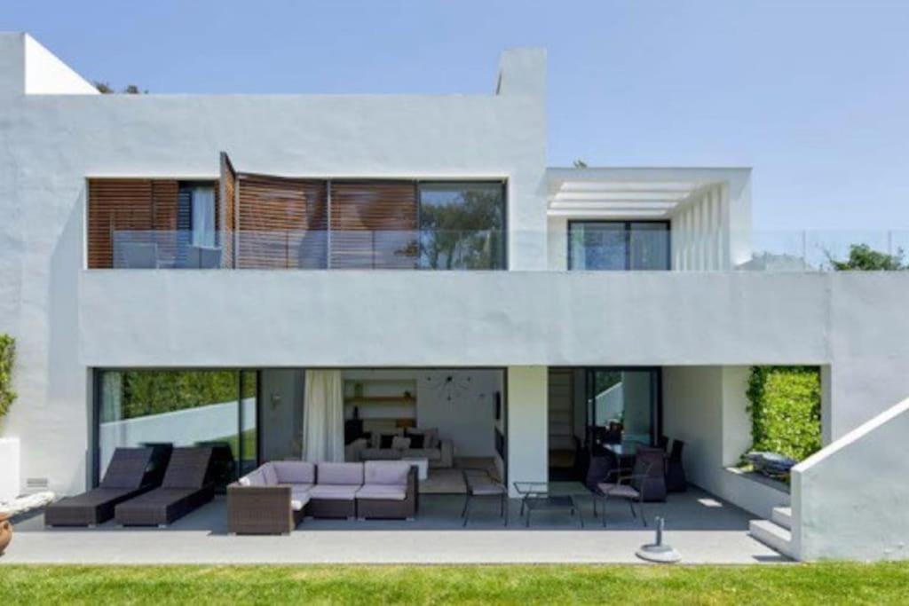 赫罗纳Camiral Golf and Wellness Luxury Villa的大型白色房屋,配有沙发和椅子
