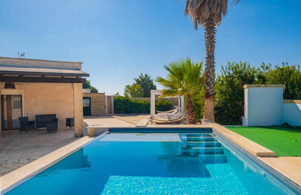 丽都玛里尼Villa Crigiada Luxury Pool的一座房子旁的游泳池,里面种着棕榈树