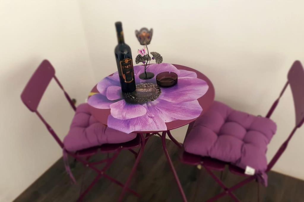 PernikЕлегантен градски апартамент с обширна тераса的紫色桌子,带一瓶葡萄酒和一朵花