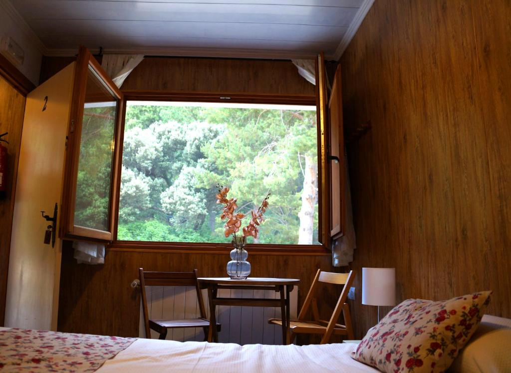 Alfara de CarlesHostal de Montaña Pous de la neu的一间卧室配有一张床、一张桌子和一个窗户。