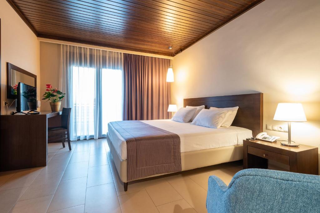 Agios Ioannis Kaspaka港口广场酒店的一间卧室配有一张床、一台电视和一张沙发