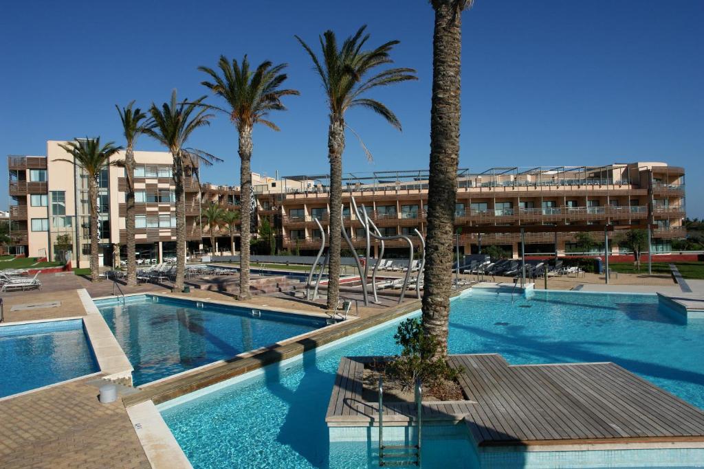 埃尔佩雷略奥利威尔斯欧特斯酒店的一座棕榈树游泳池和一座建筑