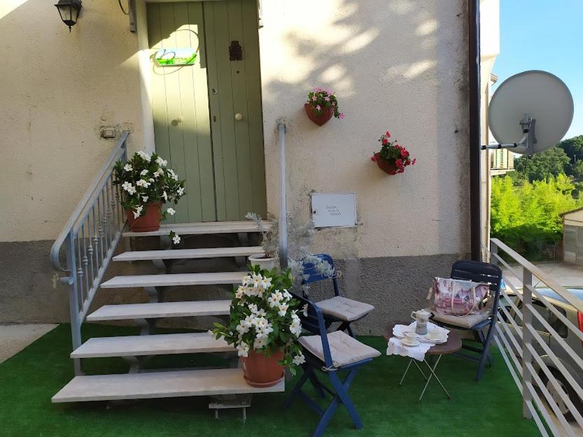 CampolattaroJolie Petite Maison的门廊设有楼梯、2把椅子和1张带鲜花的桌子