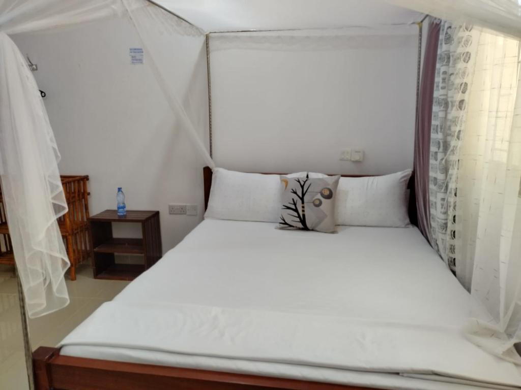 蒙巴萨6 Park Retreat的一张带白色床单和枕头的床