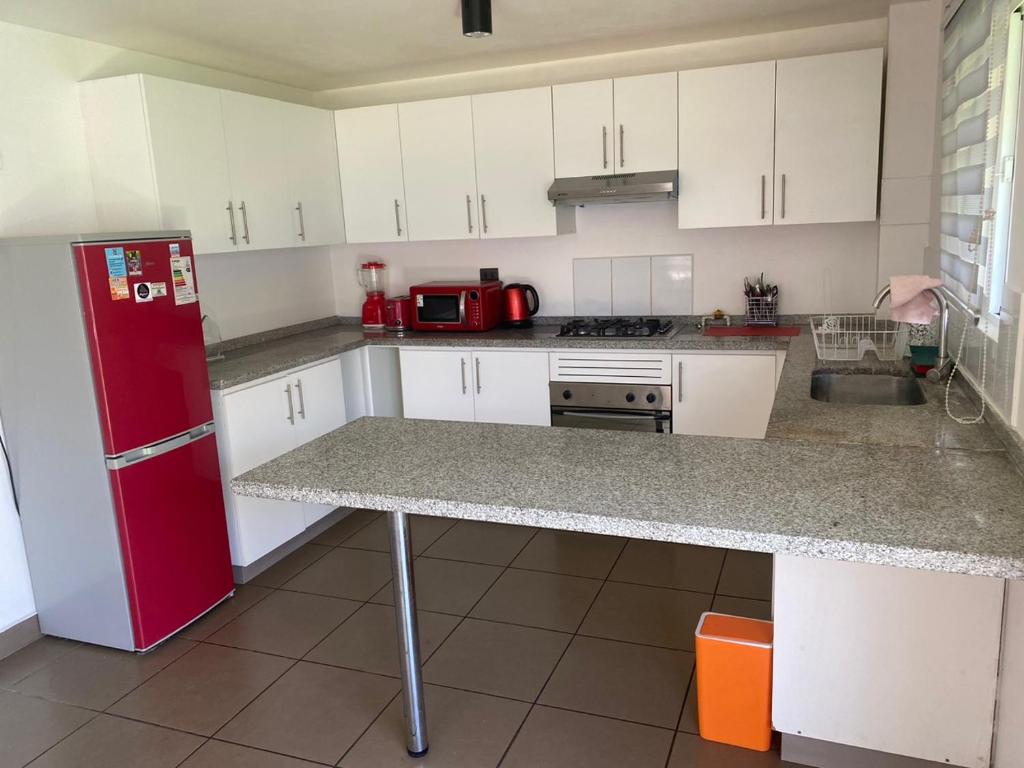 圣地亚哥Casa 3 habitaciones exclusiva valle lo campino的厨房配有白色橱柜和红色冰箱