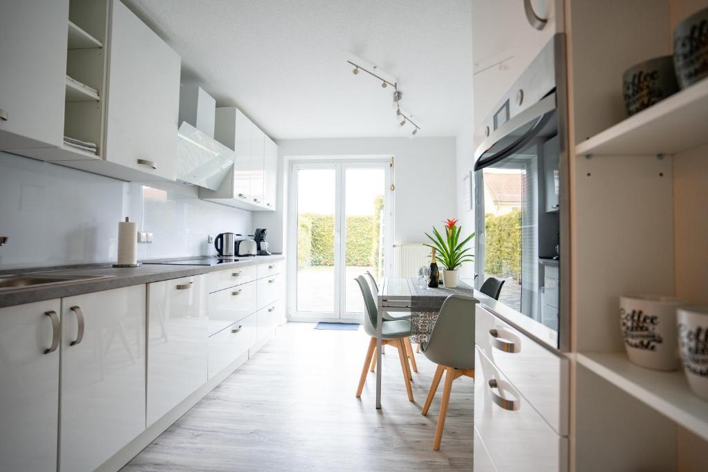 爱尔福特CaSa Apartment Svea - 2x Parken-Amazon Prime-Terasse-Garten-Vollausstattung的厨房配有白色橱柜和桌椅