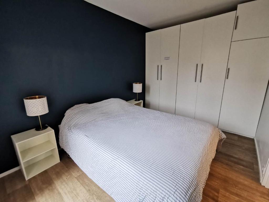 诺瑟尔Appartement Noisiel 77 (proche Disneyland & Paris)的卧室配有白色的床和蓝色的墙壁