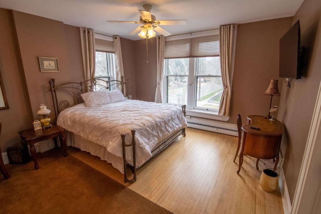 海伦娜Pope House - Hist. Mansion - The Gold Rush Suite的一间卧室配有一张带吊扇和窗户的床。