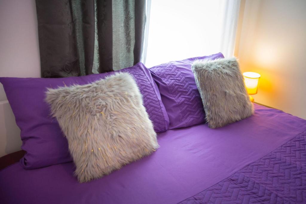 萨格勒布Apartmani Remete的紫色床上的两个枕头,带窗户