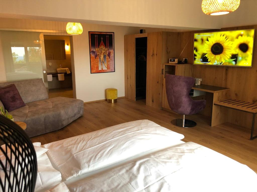 LallingThula Wellnesshotel Bayerischer Wald的一间带一张床的卧室和一间带向日葵绘画的客厅