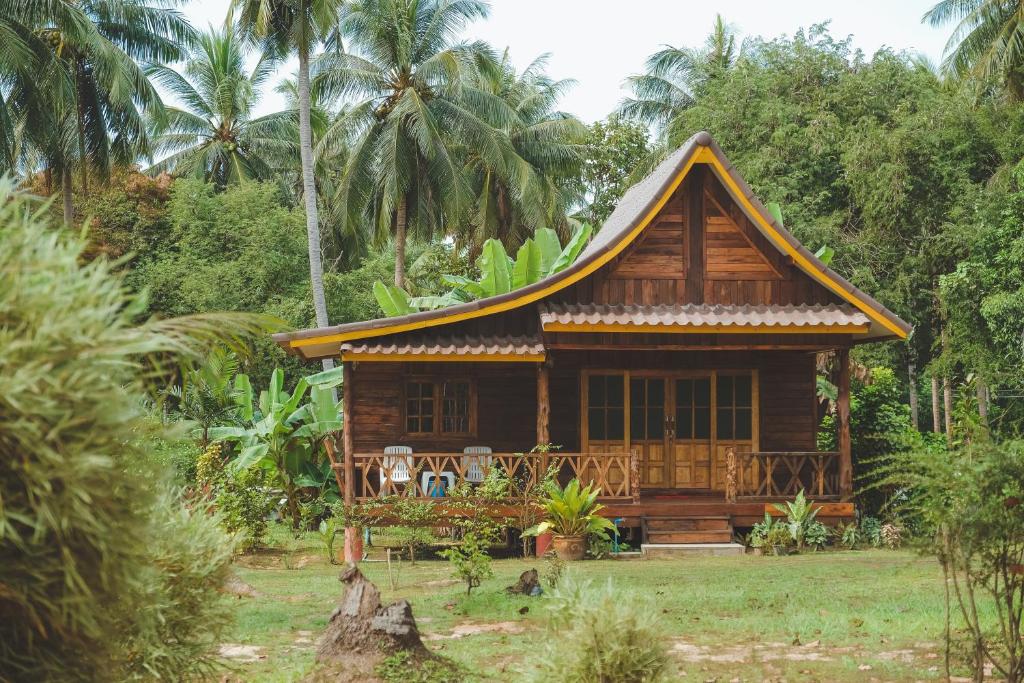 俊穆岛Kohjum Freedom Resort的棕榈树田里的一座小木房子